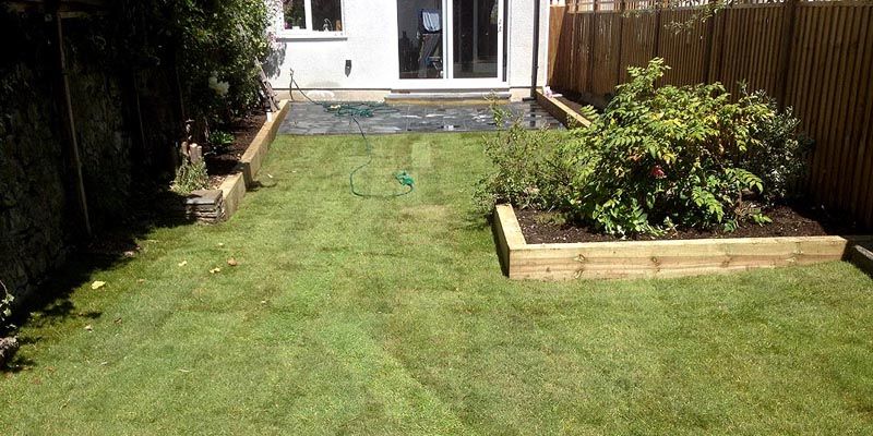 Henleaze garden after: raised sleeper beds, a black sandstone patio and new turf