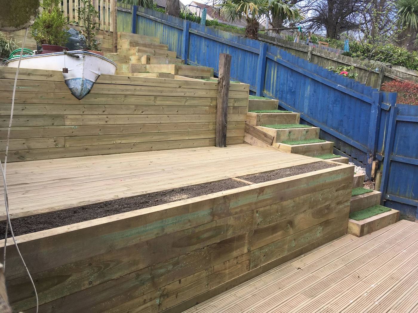 Sleeper steps and raised beds climbing a sloping garden above new decking