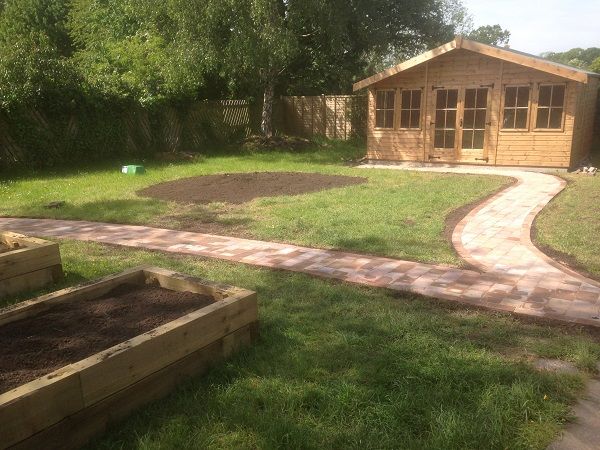 A curved path leading to a summer house across a new lawn